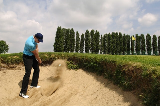 Person som slår ut en golfboll ur sandgropen